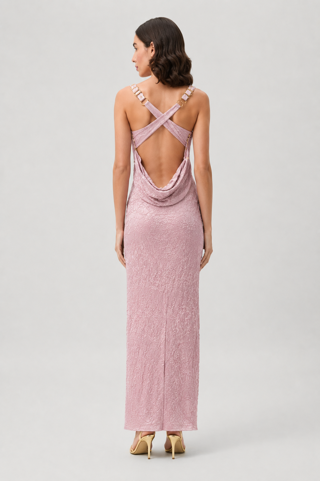 Woman wearing a pink dress with criss-cross back design on a light gray background